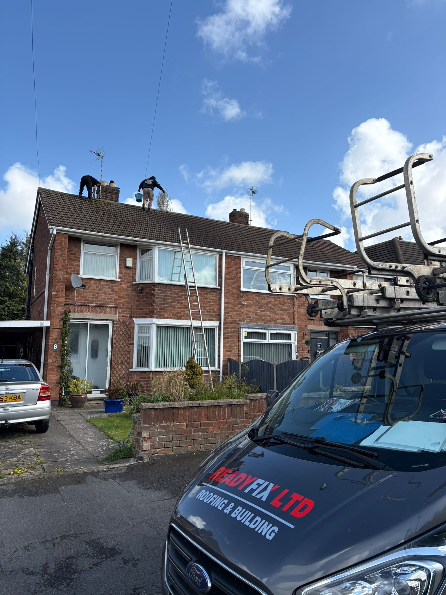 ReadyFix crew in hi-vis loading roof tiles from the company van on site